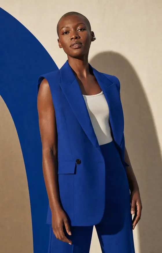 Um modelo adulto sintético em pé, usando um terno azul-cobalto